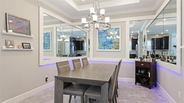 tiled dining area featuring a raised ceiling, ornamental molding, and a chandelier