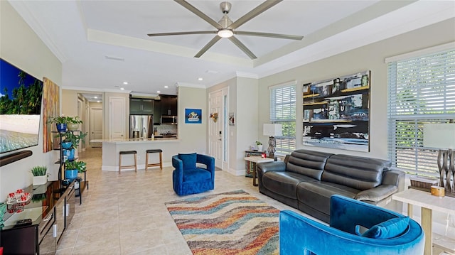 living room featuring a raised ceiling, ceiling fan, light tile patterned flooring, and ornamental molding