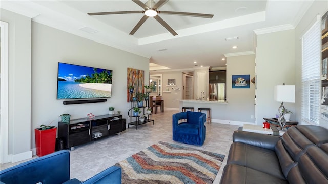 living room featuring a tray ceiling, ceiling fan, crown molding, and sink