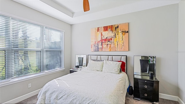 bedroom featuring carpet flooring, a tray ceiling, and ceiling fan