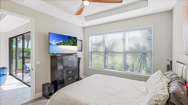 bedroom with ceiling fan, access to exterior, light tile patterned floors, and a tray ceiling