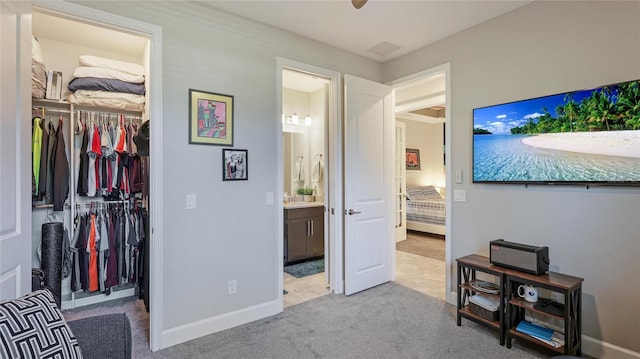 carpeted bedroom featuring ensuite bathroom, a closet, and ceiling fan