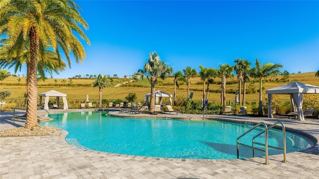 view of pool with a gazebo, a patio area, and a rural view