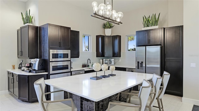 kitchen with appliances with stainless steel finishes, tasteful backsplash, dark brown cabinetry, pendant lighting, and a kitchen island