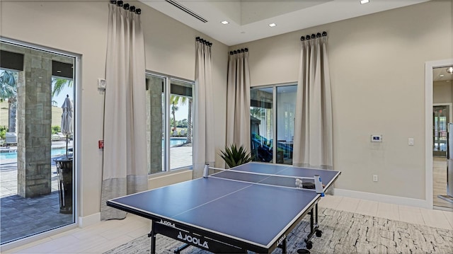 recreation room with a towering ceiling and light tile patterned floors