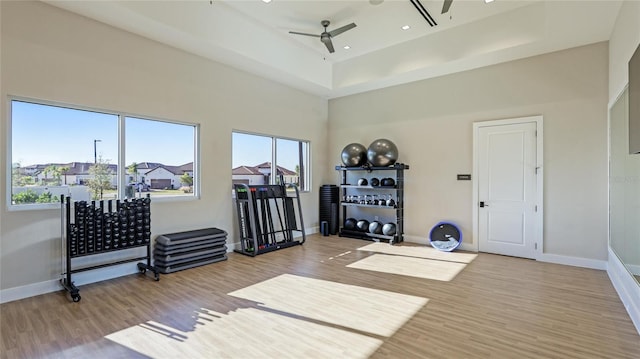 exercise area featuring ceiling fan, a towering ceiling, and wood-type flooring