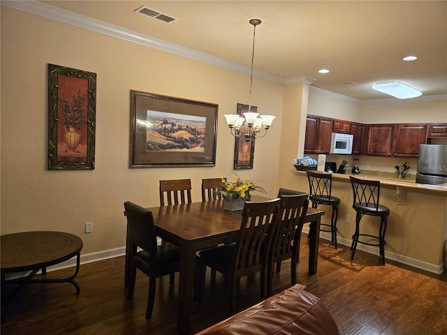 dining room with dark hardwood / wood-style flooring, ornamental molding, and a chandelier