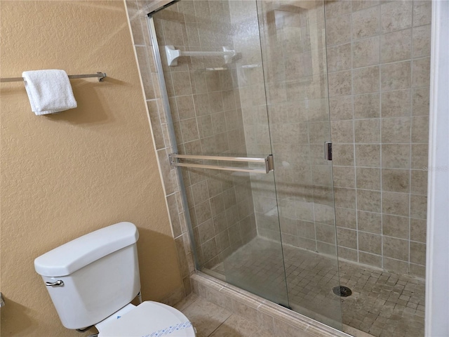 bathroom featuring toilet and a shower with door