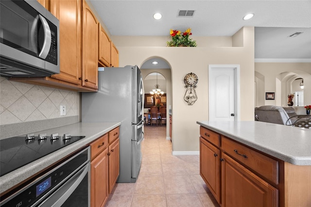 kitchen featuring stainless steel appliances, crown molding, a chandelier, decorative backsplash, and light tile patterned flooring