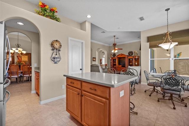 kitchen with ceiling fan with notable chandelier, light tile patterned floors, decorative light fixtures, a kitchen island, and a breakfast bar area