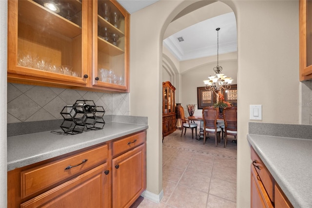 kitchen featuring tasteful backsplash, ornamental molding, light tile patterned floors, a chandelier, and hanging light fixtures