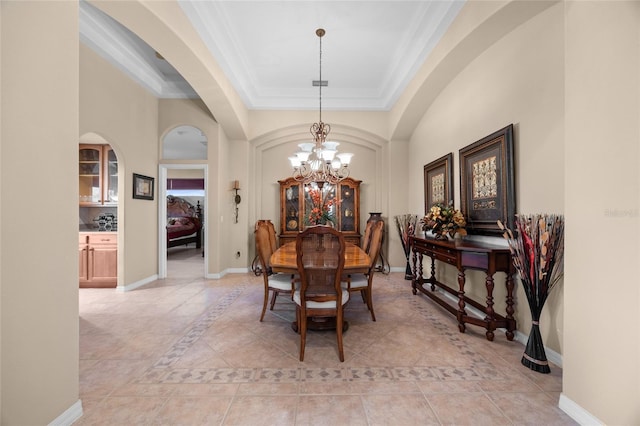 tiled dining area featuring a raised ceiling, crown molding, and a notable chandelier