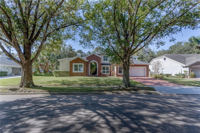 ranch-style house with an attached garage, brick siding, decorative driveway, and a front yard