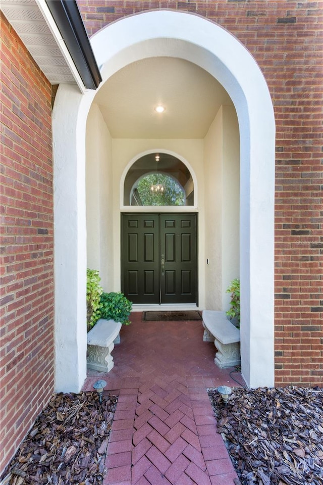 doorway to property with brick siding and stucco siding