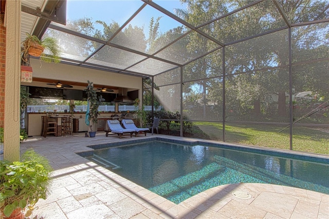 outdoor pool featuring a ceiling fan, glass enclosure, a patio, and outdoor dry bar