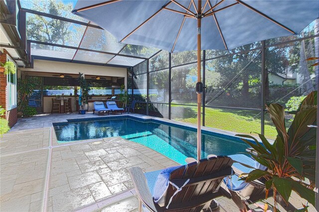 view of pool featuring outdoor dry bar, glass enclosure, a patio area, and a ceiling fan