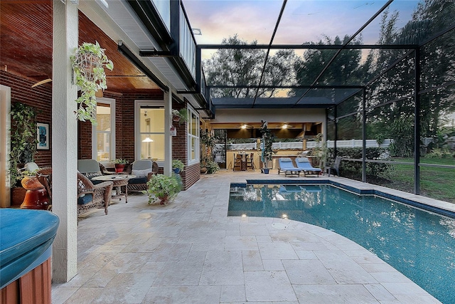 pool at dusk with an outdoor pool, outdoor dry bar, a lanai, a patio area, and outdoor lounge area