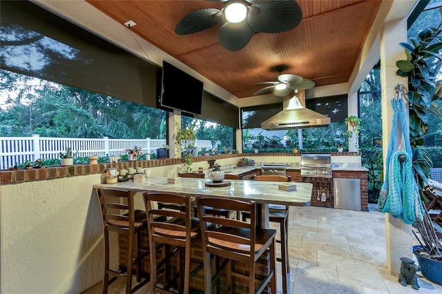 view of patio with a ceiling fan, area for grilling, fence, and a bar