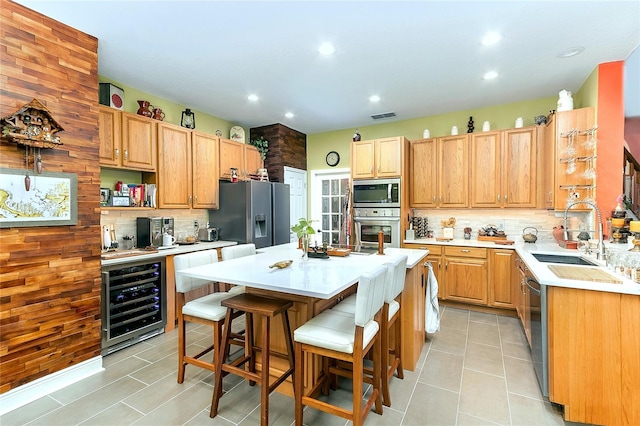 kitchen featuring beverage cooler, stainless steel appliances, a kitchen island, and light countertops