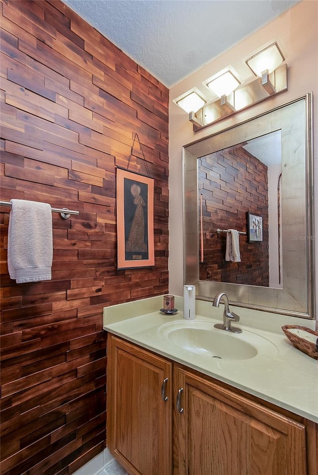 bathroom with wood walls, a textured ceiling, and vanity