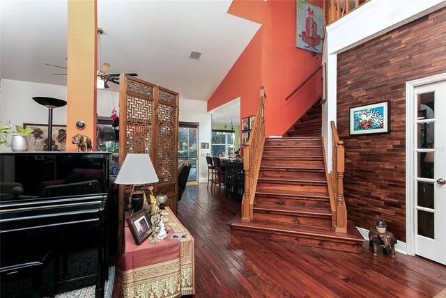 stairway featuring hardwood / wood-style flooring, visible vents, high vaulted ceiling, and a ceiling fan