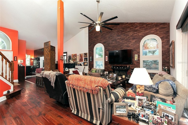 living area with high vaulted ceiling, ceiling fan, stairway, and dark wood-style flooring