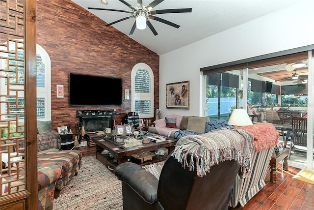 living area featuring ceiling fan, high vaulted ceiling, wood finished floors, and a large fireplace