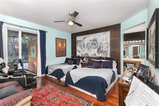 bedroom featuring a textured ceiling, an accent wall, and dark wood finished floors