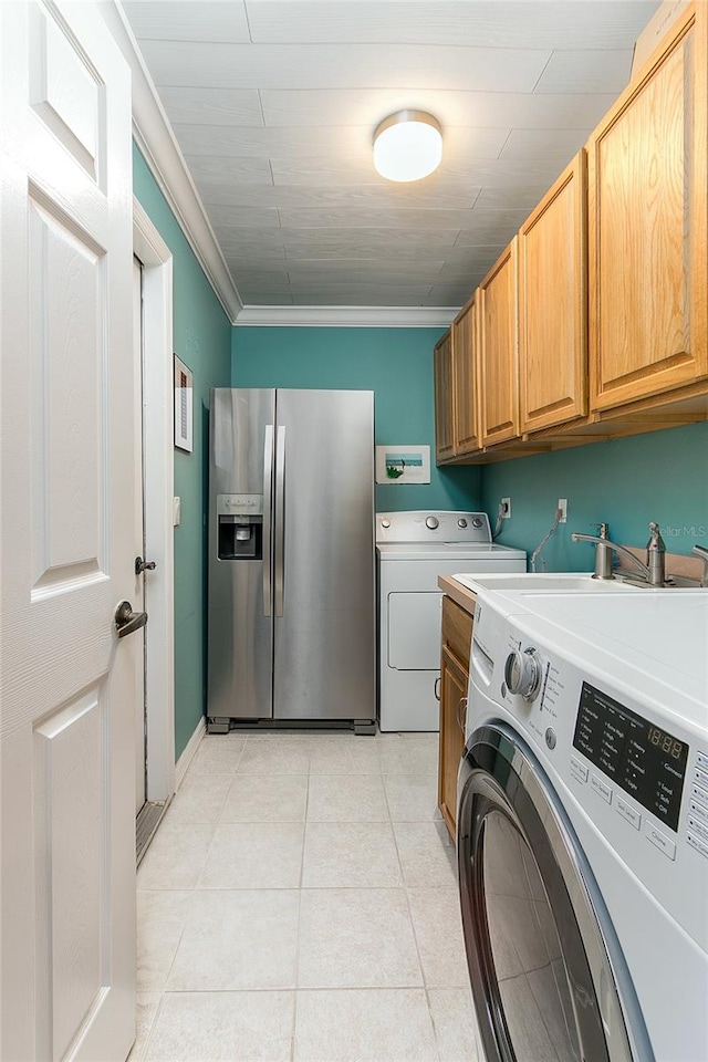 laundry room featuring cabinet space, washing machine and dryer, light tile patterned floors, and ornamental molding