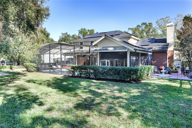 rear view of property with a lawn, a chimney, a sunroom, and an outdoor pool