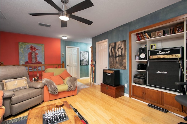 living room with visible vents, light wood-style floors, ceiling fan, a textured ceiling, and baseboards