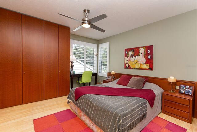 bedroom featuring ceiling fan, a textured ceiling, and light wood-style floors