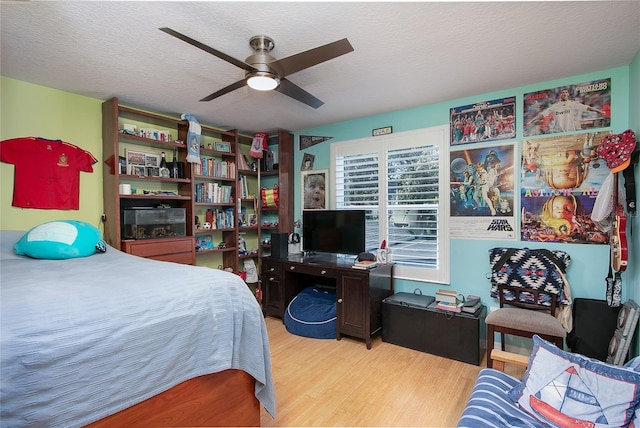 bedroom featuring light wood-style flooring, a ceiling fan, and a textured ceiling