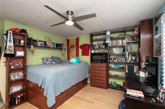 bedroom with a textured ceiling, light wood-type flooring, and a ceiling fan