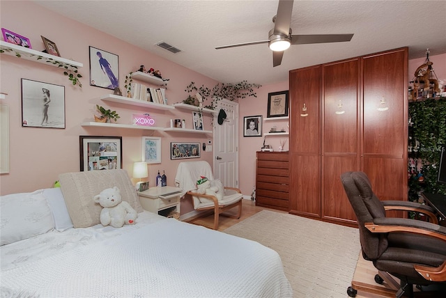 bedroom with visible vents, ceiling fan, a textured ceiling, and wood finished floors