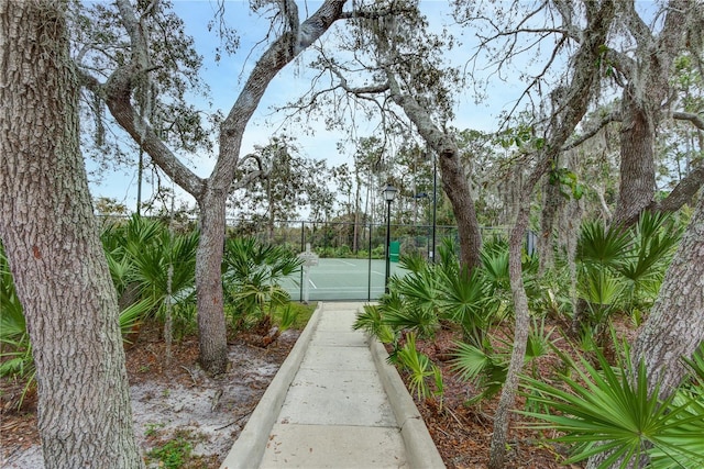 view of community with a tennis court and fence