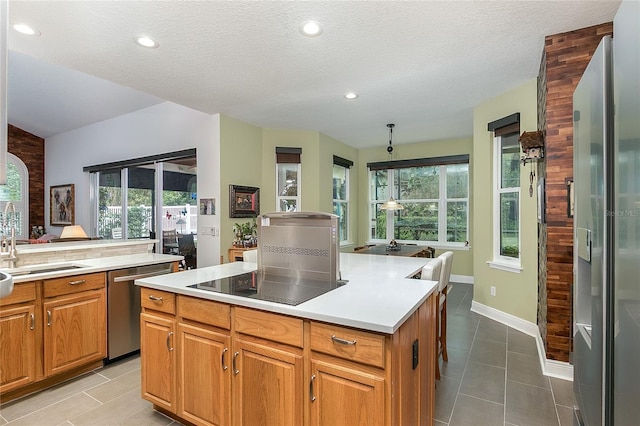 kitchen with a kitchen island, appliances with stainless steel finishes, brown cabinets, tile patterned flooring, and light countertops