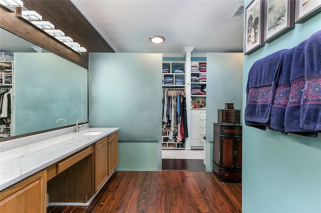 bathroom featuring a walk in closet, visible vents, vanity, and wood finished floors