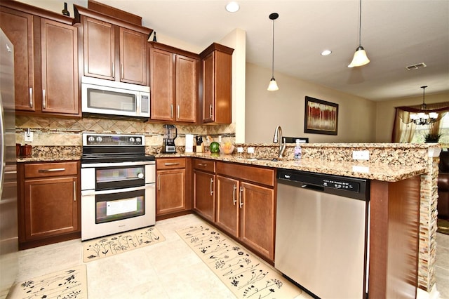 kitchen with sink, stainless steel appliances, decorative light fixtures, and kitchen peninsula