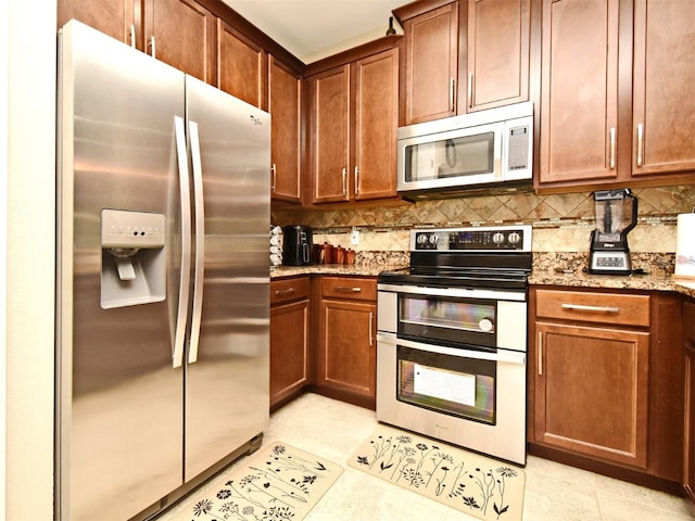 kitchen with light stone countertops, appliances with stainless steel finishes, light tile patterned floors, and tasteful backsplash