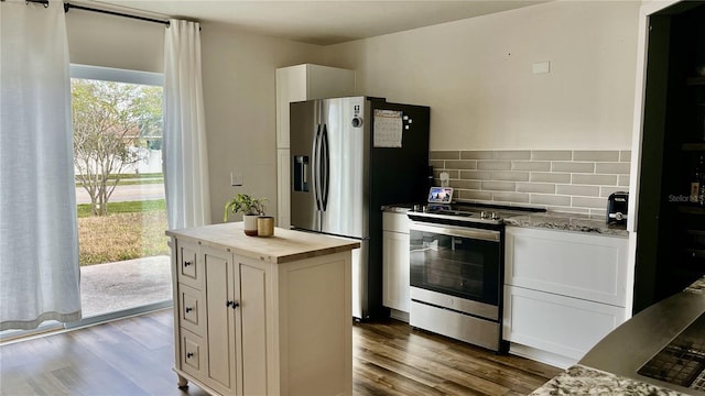 kitchen featuring white cabinetry, a center island, light stone counters, dark hardwood / wood-style flooring, and appliances with stainless steel finishes