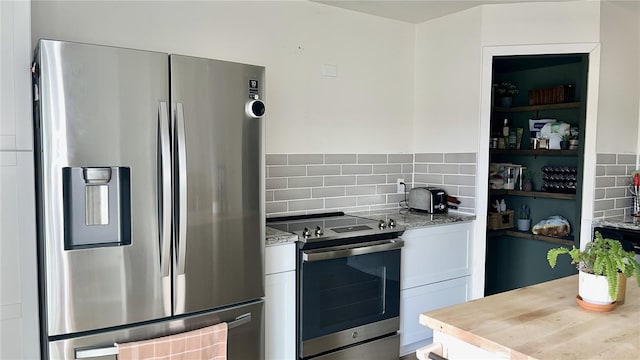 kitchen with backsplash, light stone countertops, white cabinets, and stainless steel appliances