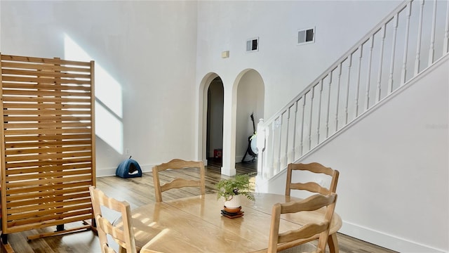 dining area with wood-type flooring and a towering ceiling