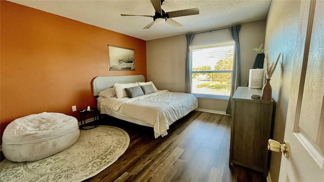 bedroom with ceiling fan, dark hardwood / wood-style floors, and a textured ceiling