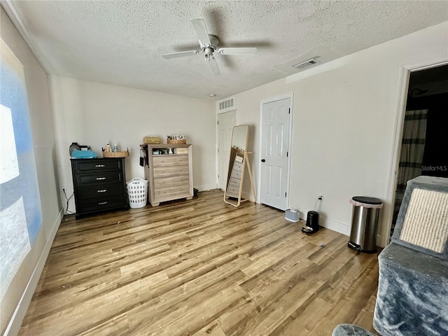 bedroom with ceiling fan, a textured ceiling, and hardwood / wood-style flooring