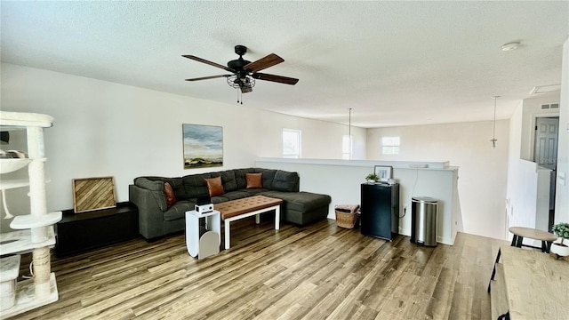 living room featuring a textured ceiling, light wood-type flooring, and ceiling fan