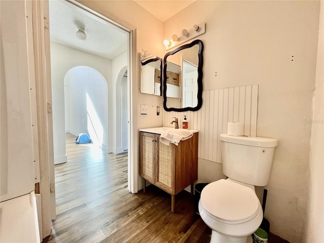 bathroom with hardwood / wood-style flooring, vanity, toilet, and a textured ceiling