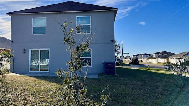 view of side of home with a lawn and central AC