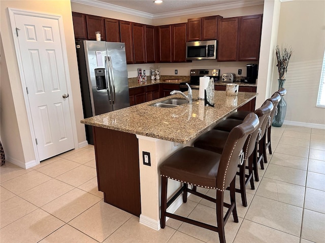 kitchen with sink, stainless steel appliances, a breakfast bar, a center island with sink, and ornamental molding