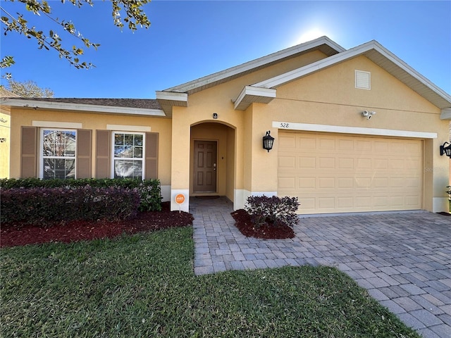 ranch-style home with an attached garage, decorative driveway, and stucco siding